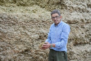 Andrew stood in front of his Maize yield holding a handful of Maize.